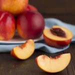 Slice Of Nectarine And Whole Fruits On A Wooden Table.