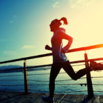 healthy lifestyle sports woman running on wooden boardwalk sunri