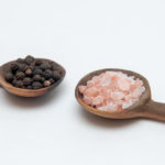 Salt And Pepper Seasonings Of Pepper Corns And Rock Salt On Wood