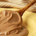 Creamy swirls of peanut butter on a vintage wooden spoon resting