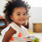 Happy Baby Girl Playing With Toys In Playroom