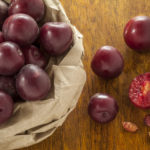 Red Plums In Brown Paper Bag