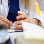 Female Medicine Doctor Hand Hold Jar Of Pills And Write Prescrip